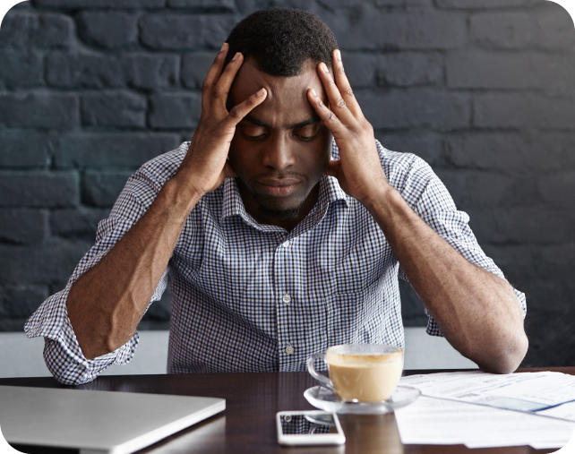 A stressed Nigerian worker holding his head at a desk